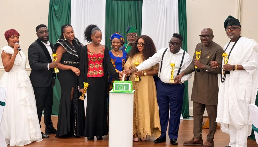 A group gathered on stage around a celebration cake.