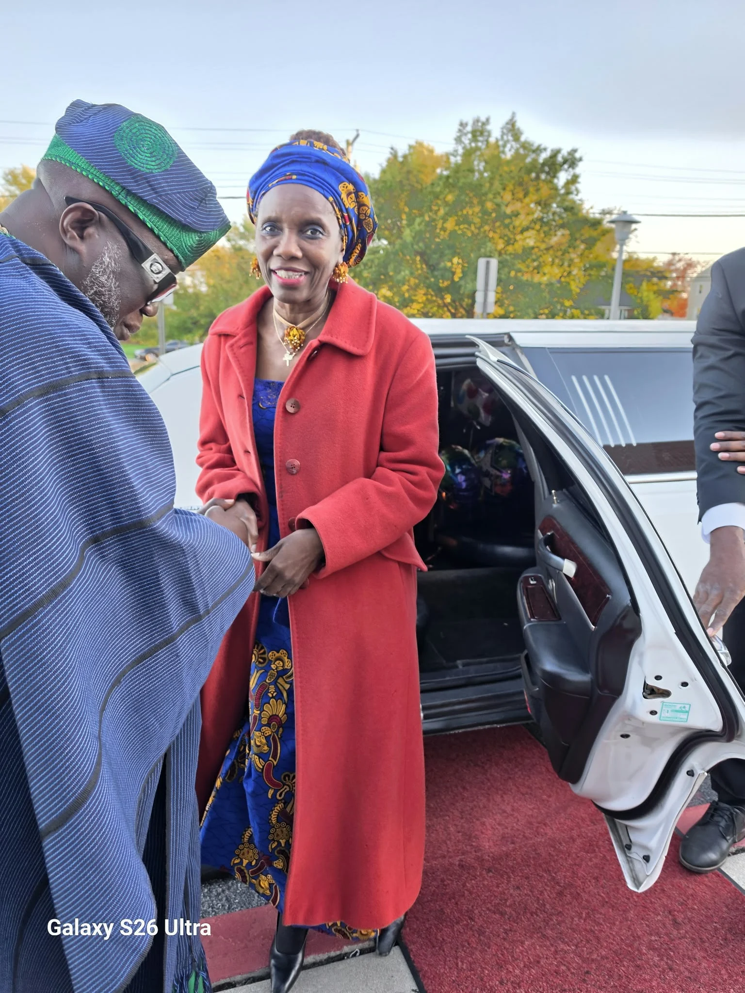 Dr. O arriving at the celebration in blue and gold attire with a red coat.