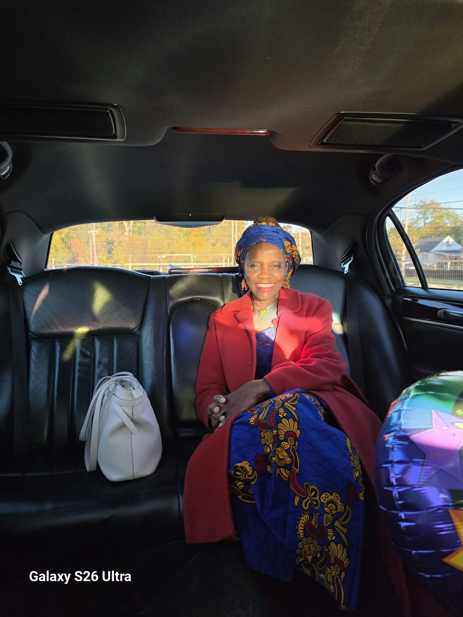 Dr. O seated in a vehicle wearing blue and gold attire.