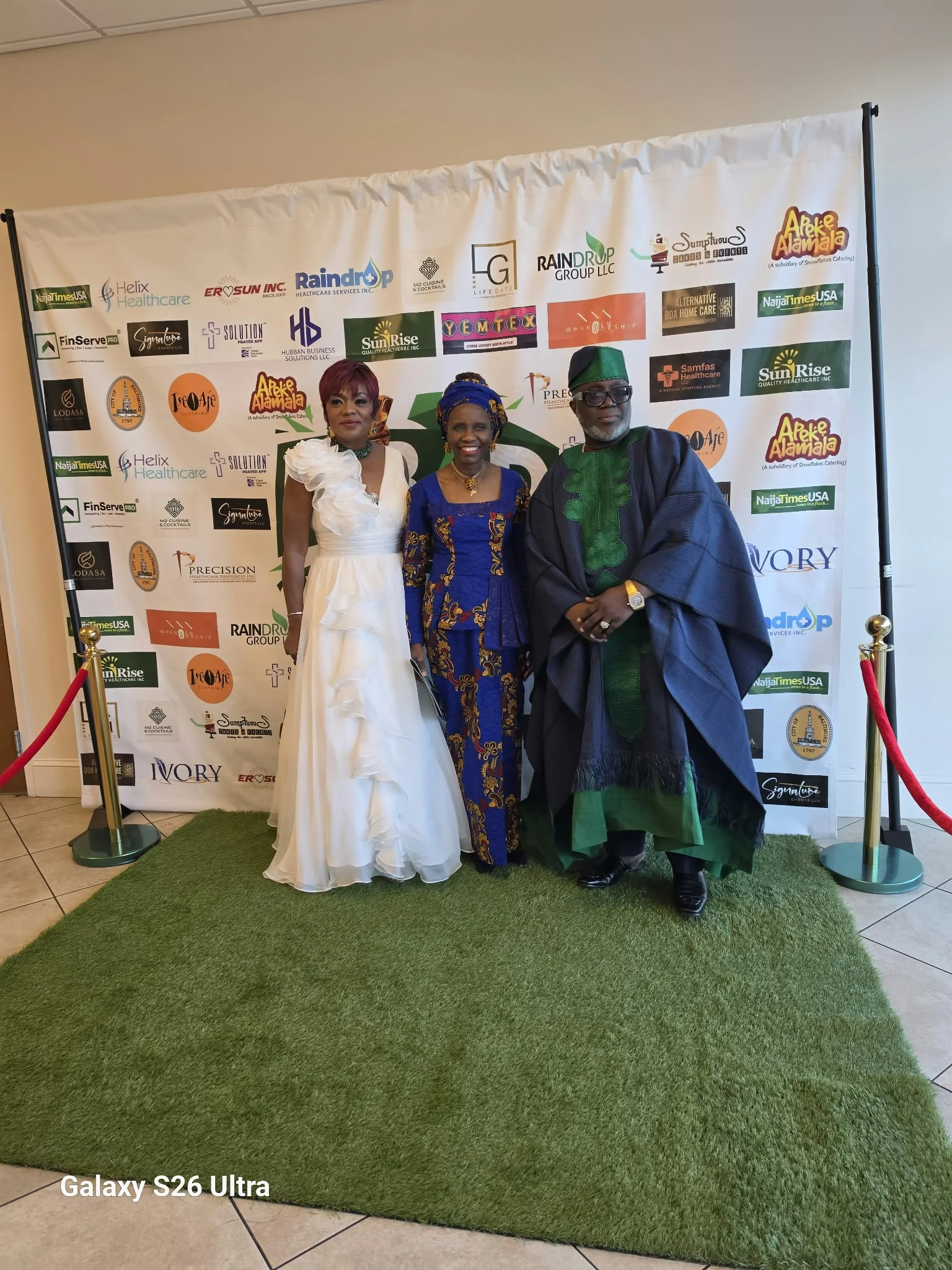 A group in formal and traditional attire posing at the event backdrop.
